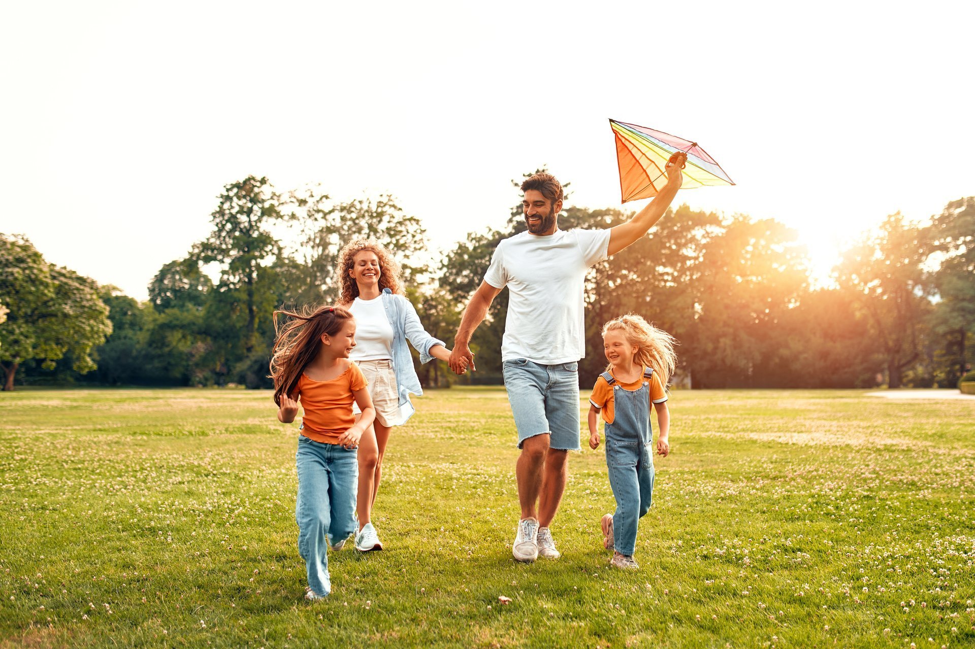 Happy family running and playing with a kite in a park