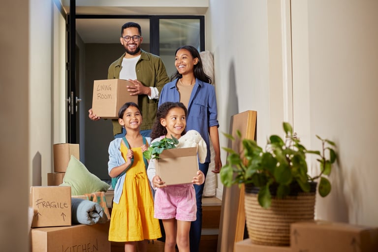 Happy mixed race family moving into a new home together carrying cardboard boxes