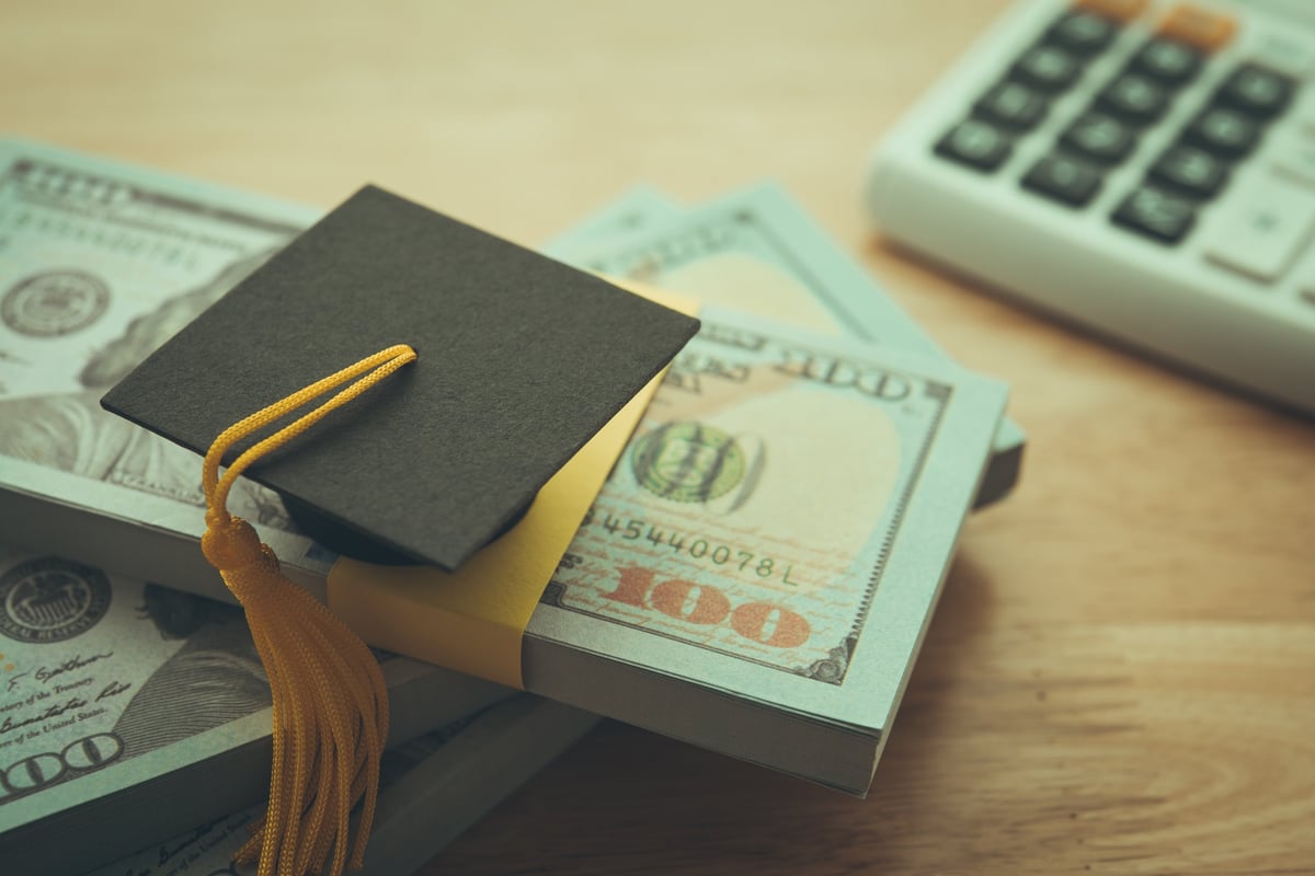 Graduation cap university on stack US dollar banknote and calculator representing education expense budget plan, tuition concept and student loan