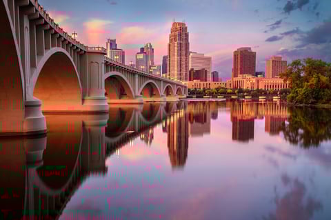 City skyline reflected in calm river at sunrise with modern buildings