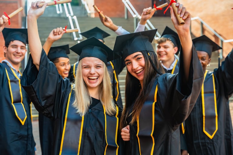 Diverse students wearing graduation caps and gowns are holding up their diplomas, cheering happily and celebrating their academic achievement and educational success together