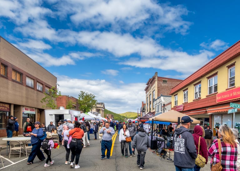Spring fair festival with local vendors, food trucks, and crowds under a blue sky capturing a lively community atmosphere