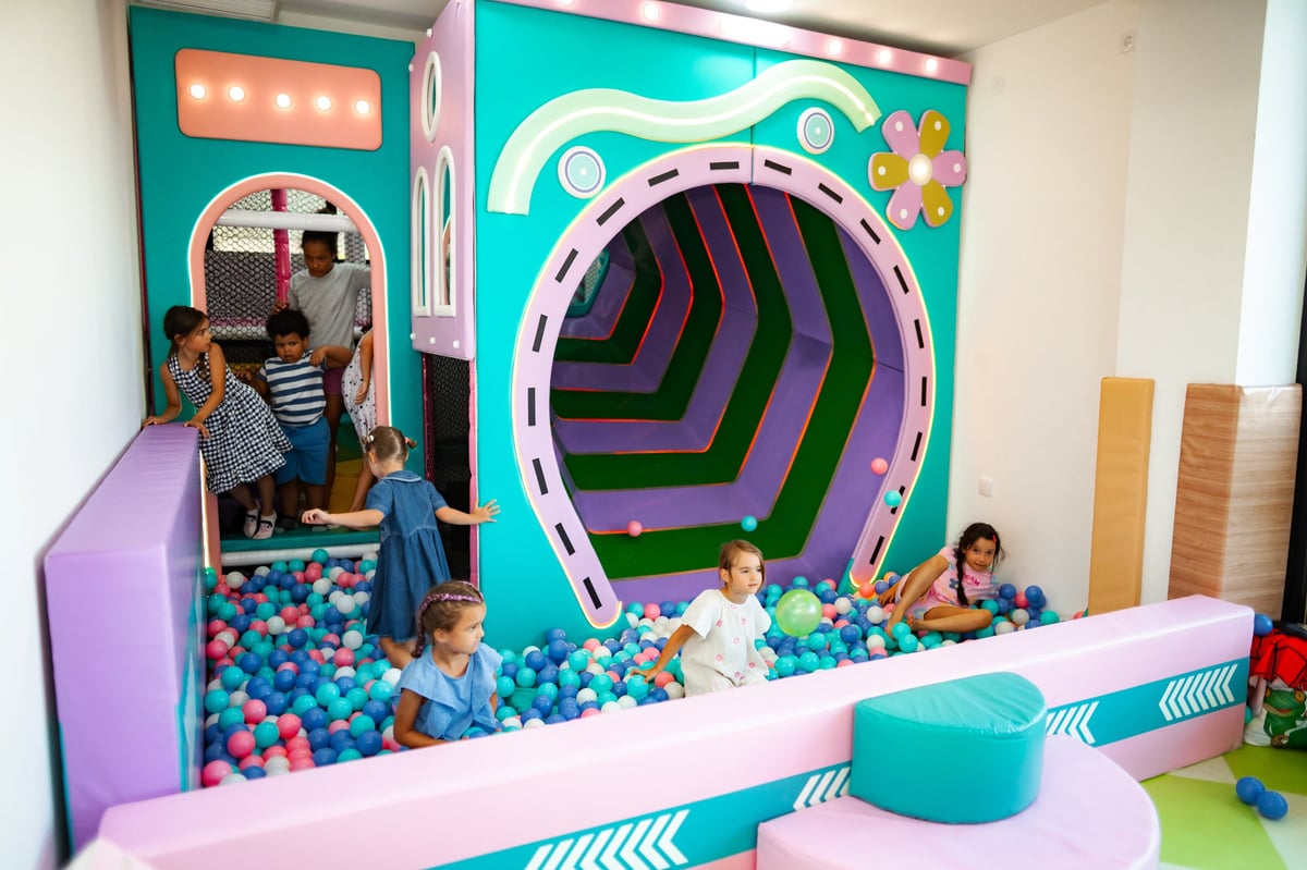 Group of happy children playing and sliding in a vibrant indoor ball pit