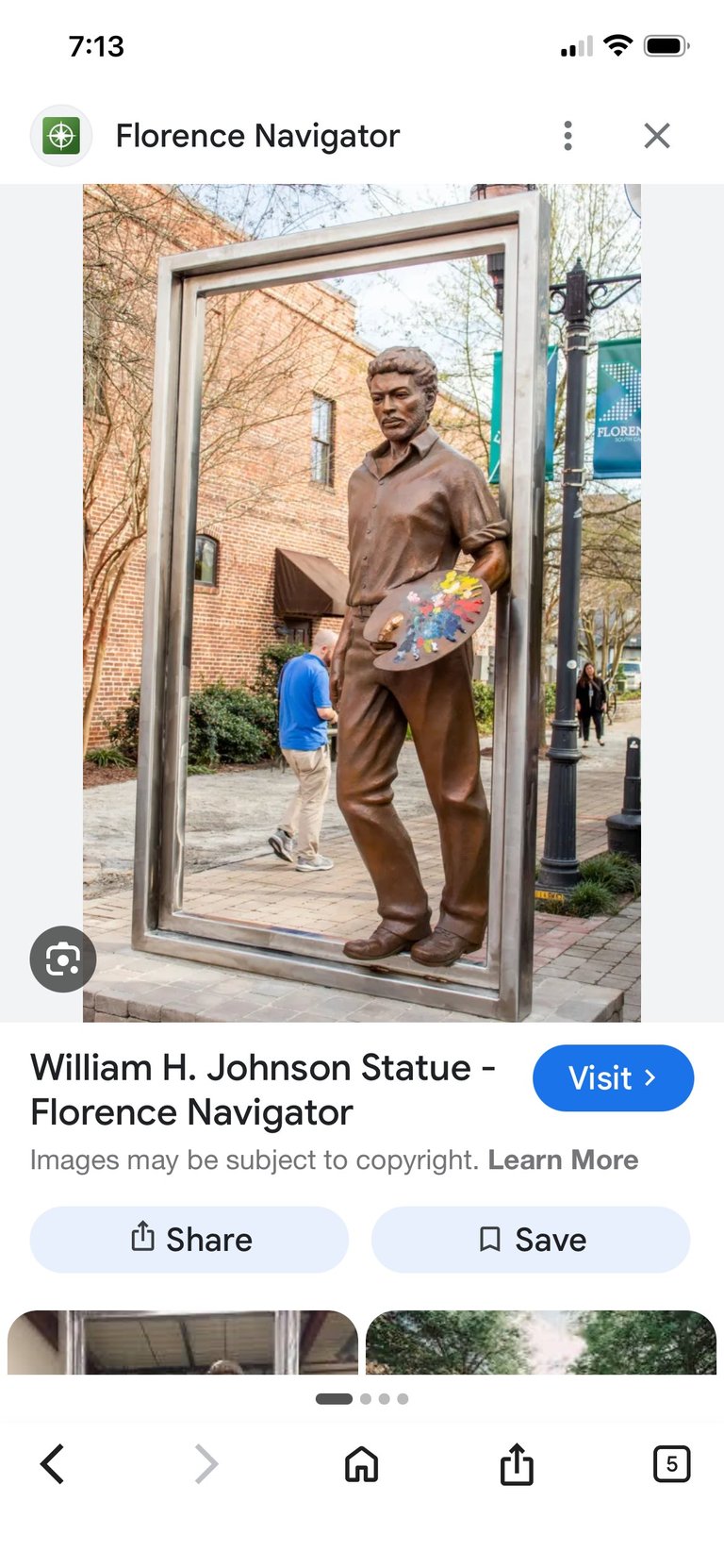Bronze statue of William H. Johnson holding a skateboard, displayed in a large picture frame on a city street